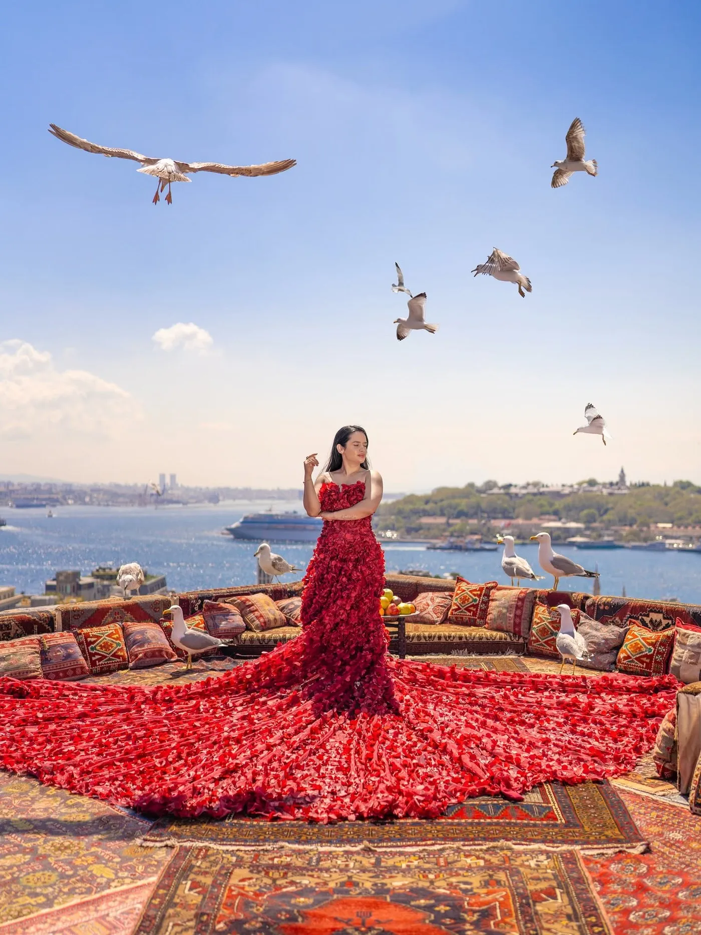 Asiya Bhandari, UGC creator, in a red floral gown on a rooftop terrace overlooking the water